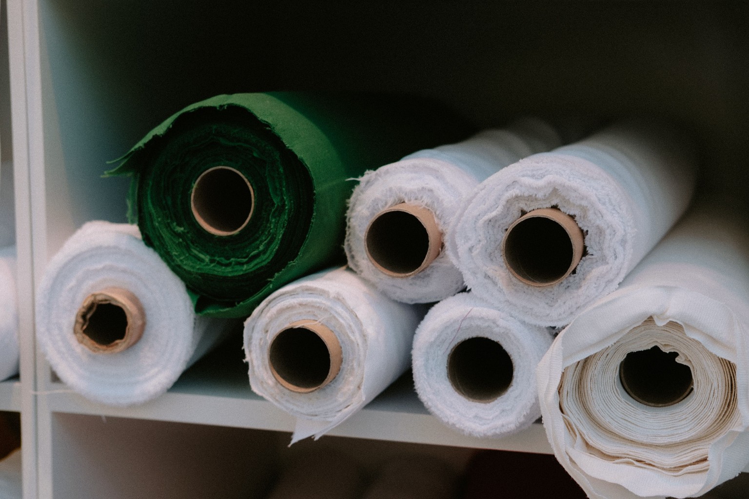 Rolls of white and green fabric stored on shelving