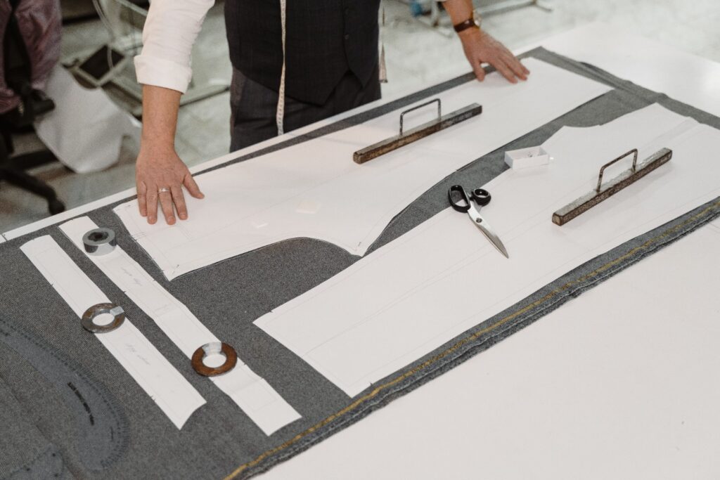 Trouser paper pattern positioned over grey fabric on a cutting table